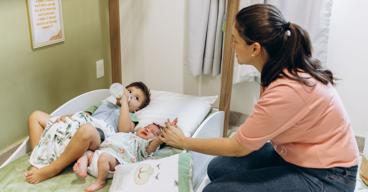 A mother sits with her children on a bed, fostering a warm and nurturing atmosphere.